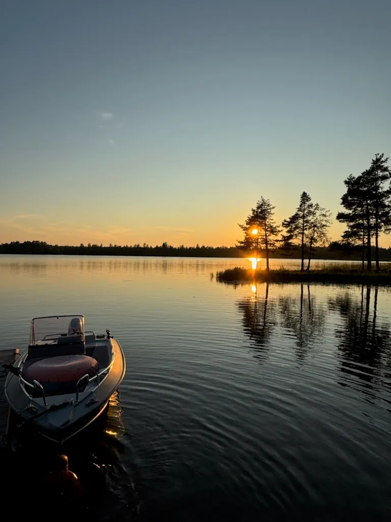 Motorbåt vid en brygga på Dalälven i solnedgång.