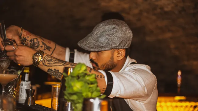 Ein Barkeeper bereitet an der Bar ein Getränk mit Minze zu.