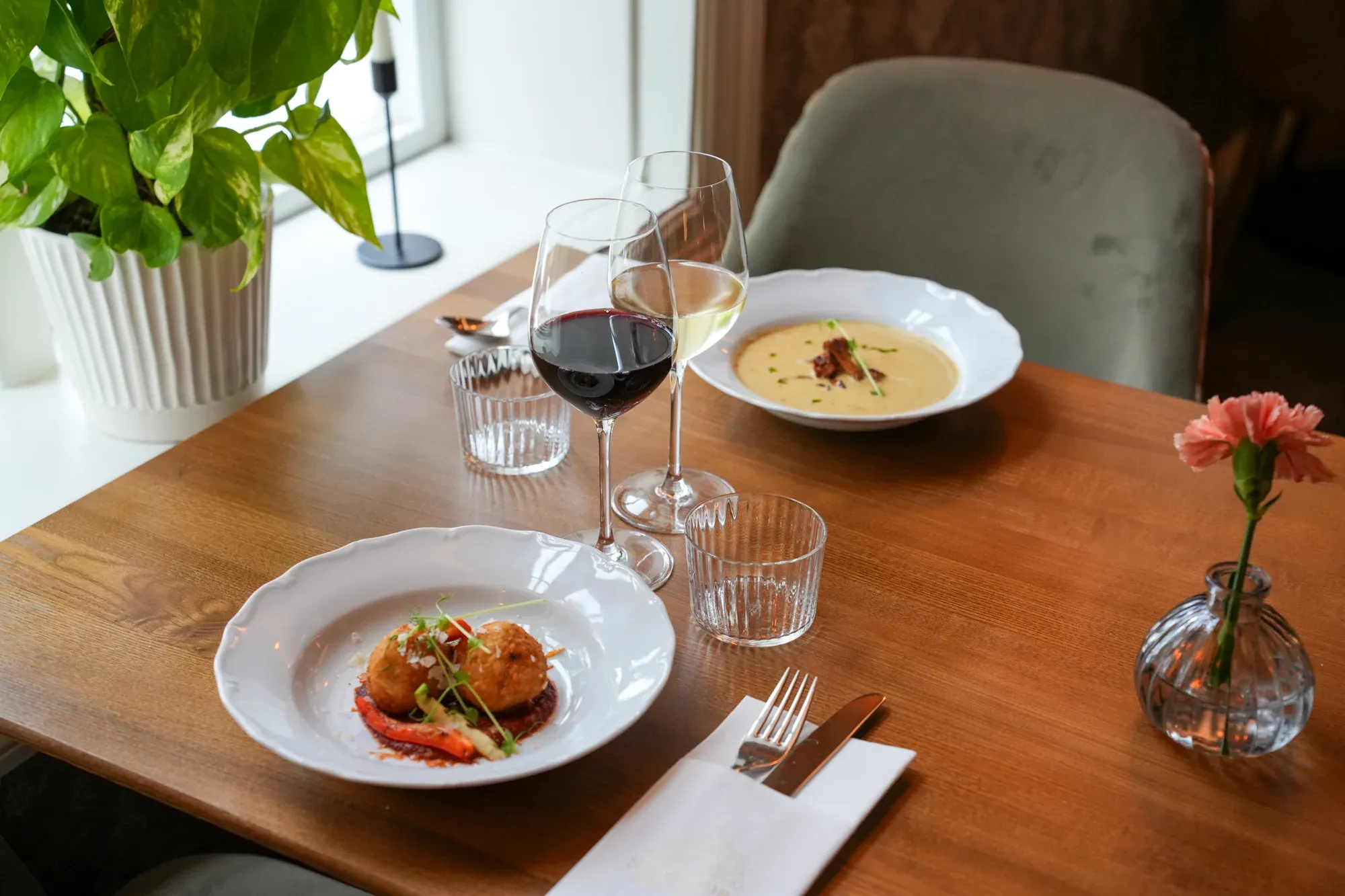 Dukat bord med rätter, vinglas och blommor i herrgårdens restaurang.