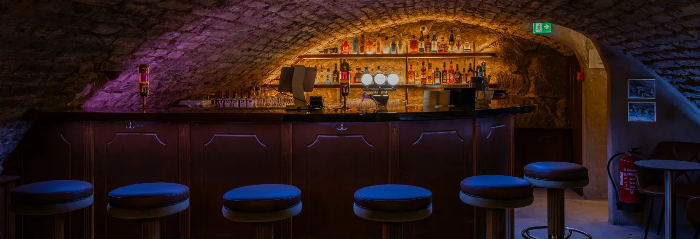 Die Bar im gewölbten Kellerraum mit beleuchteten Flaschenregalen.