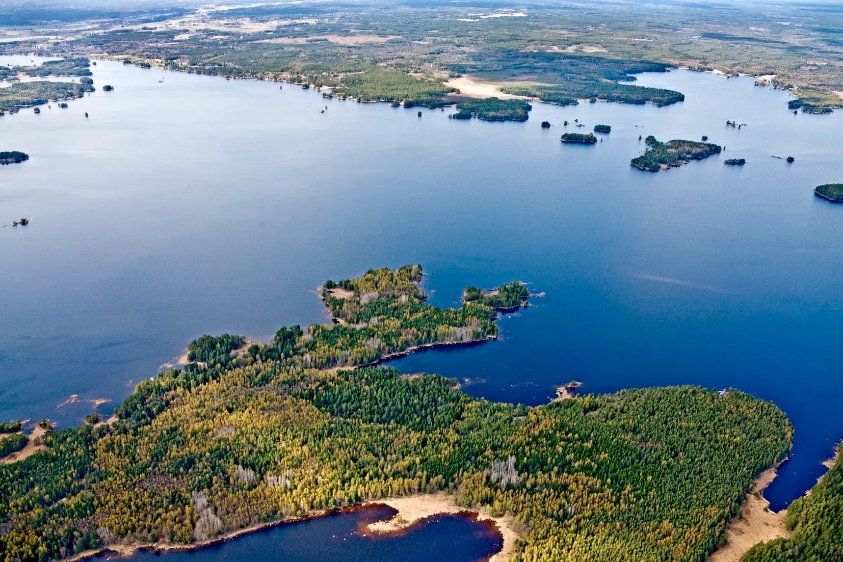 Flygbild över Dalälvens vida vatten och skogsklädda öar.